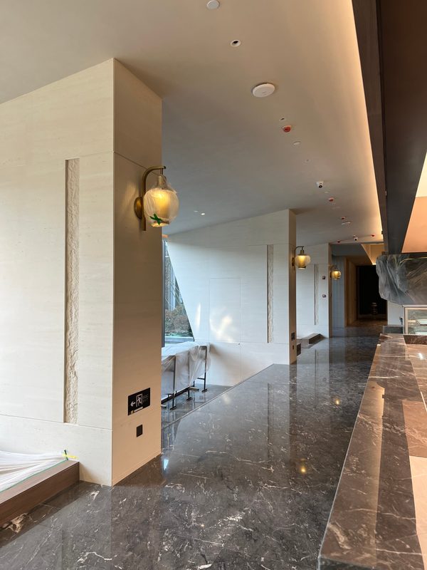 Cast travertine corridor with vertical reveals and wall lights