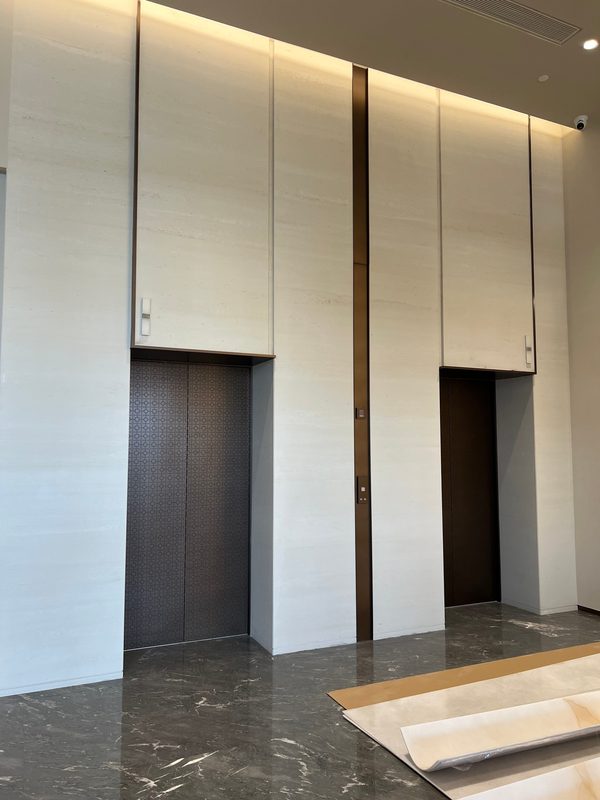 Cast travertine lift lobby with bronze reveals and cove lighting